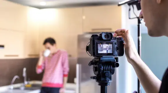  A photographer shoots a man sipping on something in a kitchen