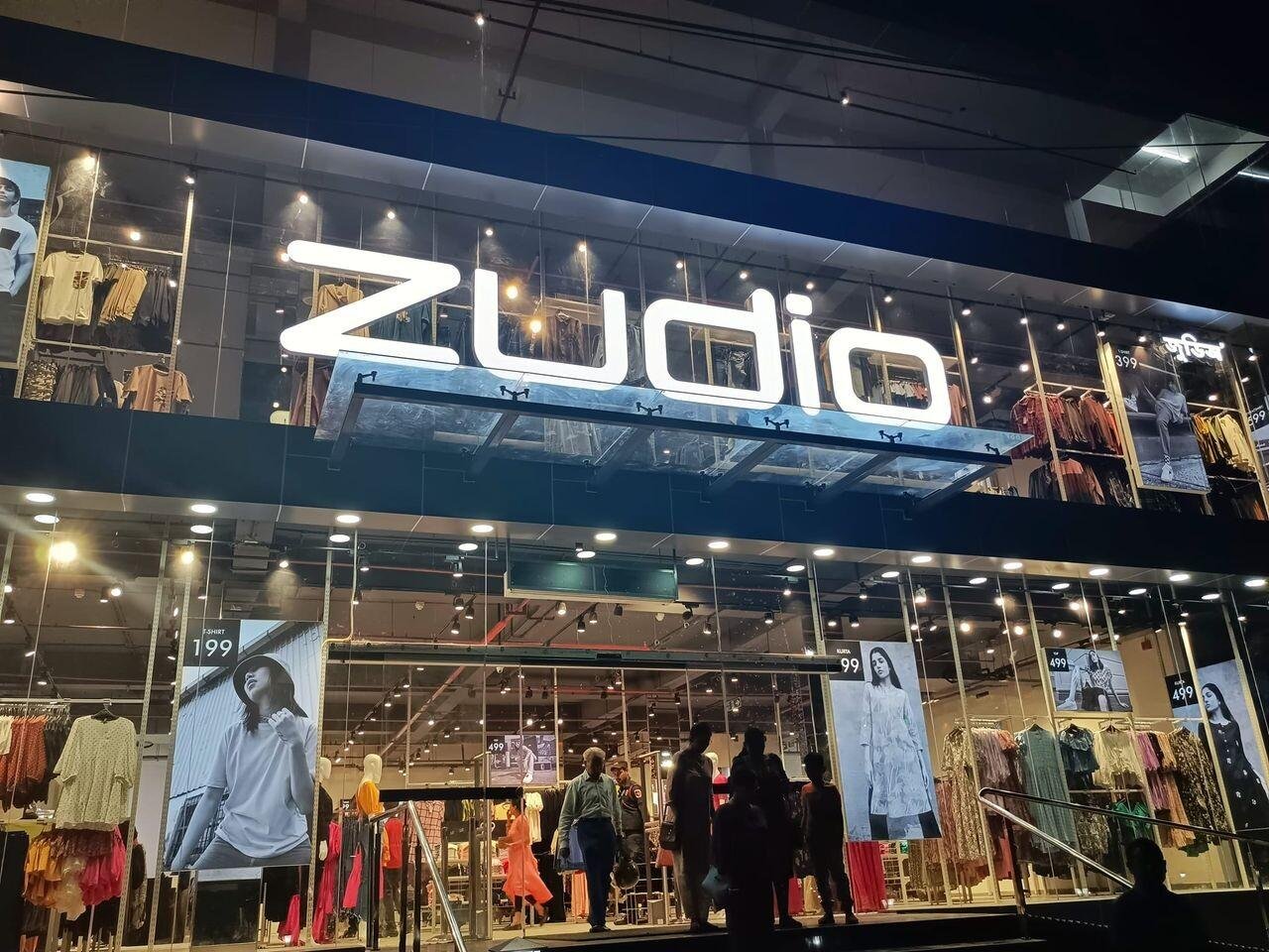 The glass facade of a lit Zudio inside a mall