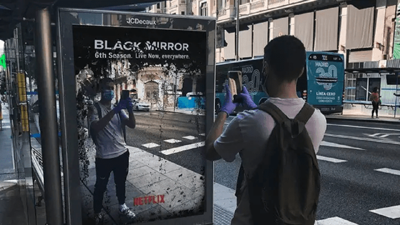 A man clicks on an image of himself on an interactive mirror banner of a Netflix show
