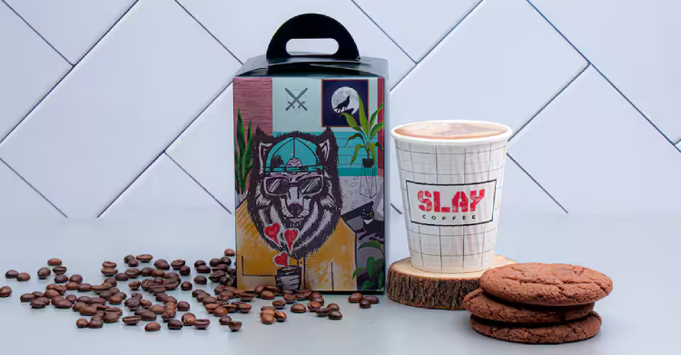 A box of Slay Coffee’s quirky fox artwork with its cup of coffee beside it
