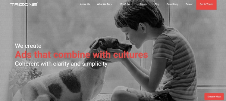 Trizone website banner showing a child gently holding a dog’s face, with the text “We create ads that combine with cultures, coherent with clarity and simplicity.” 