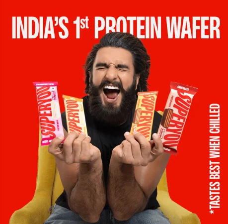 Ranveer Singh holding multiple SuperYou protein wafer bars against a bright red background. 