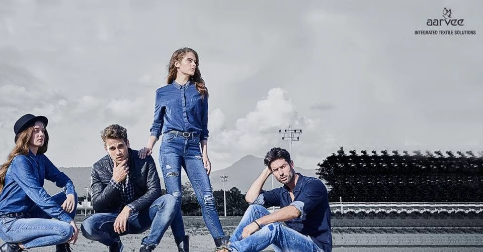Fashion banner featuring four models in denim outfits posing outdoors against a muted landscape, with the Aarvee Integrated Textile Solutions logo 
