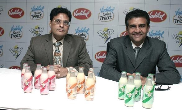 Two Vadilal executives seated at a table with Power Sip flavoured milk bottles